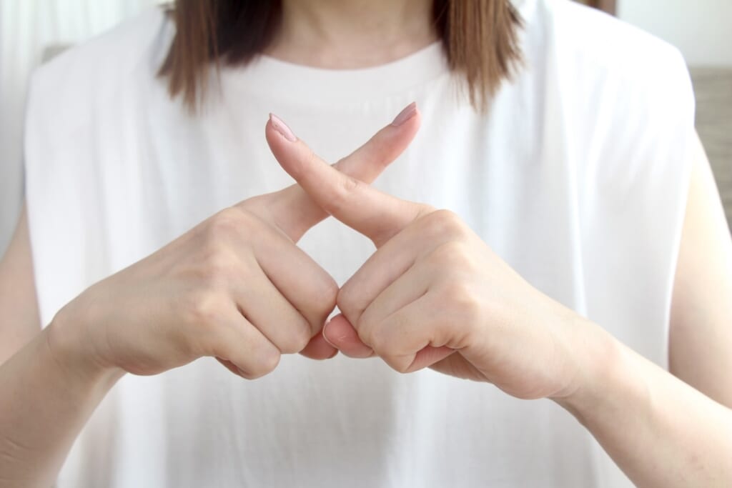 妊娠初期に気をつけるべきサプリや成分をイメージして指でバツ印をつくる女性の写真