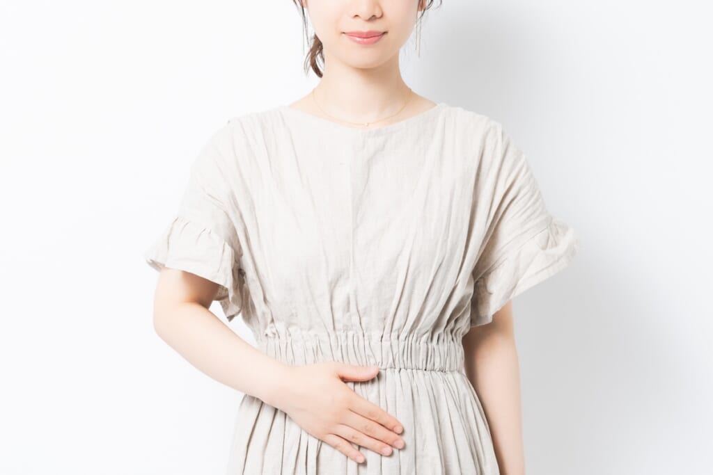 お腹に手を添えてラクトフェリンで妊活に向けた子宮内フローラを整える女性