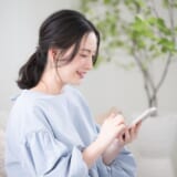 スマートフォンを手に考える日本人女性