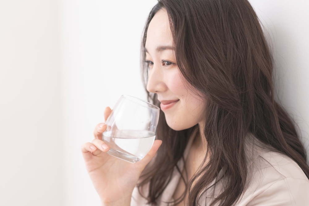 自宅で水を飲む日本人女性