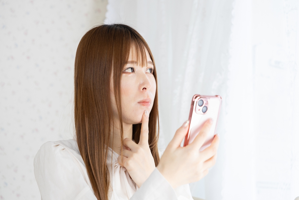 スマートフォンを見て悩む日本人女性
