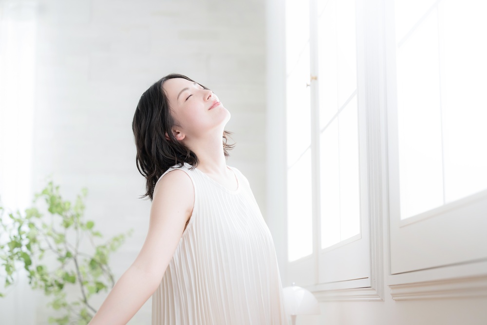 窓辺で伸びをする日本人女性